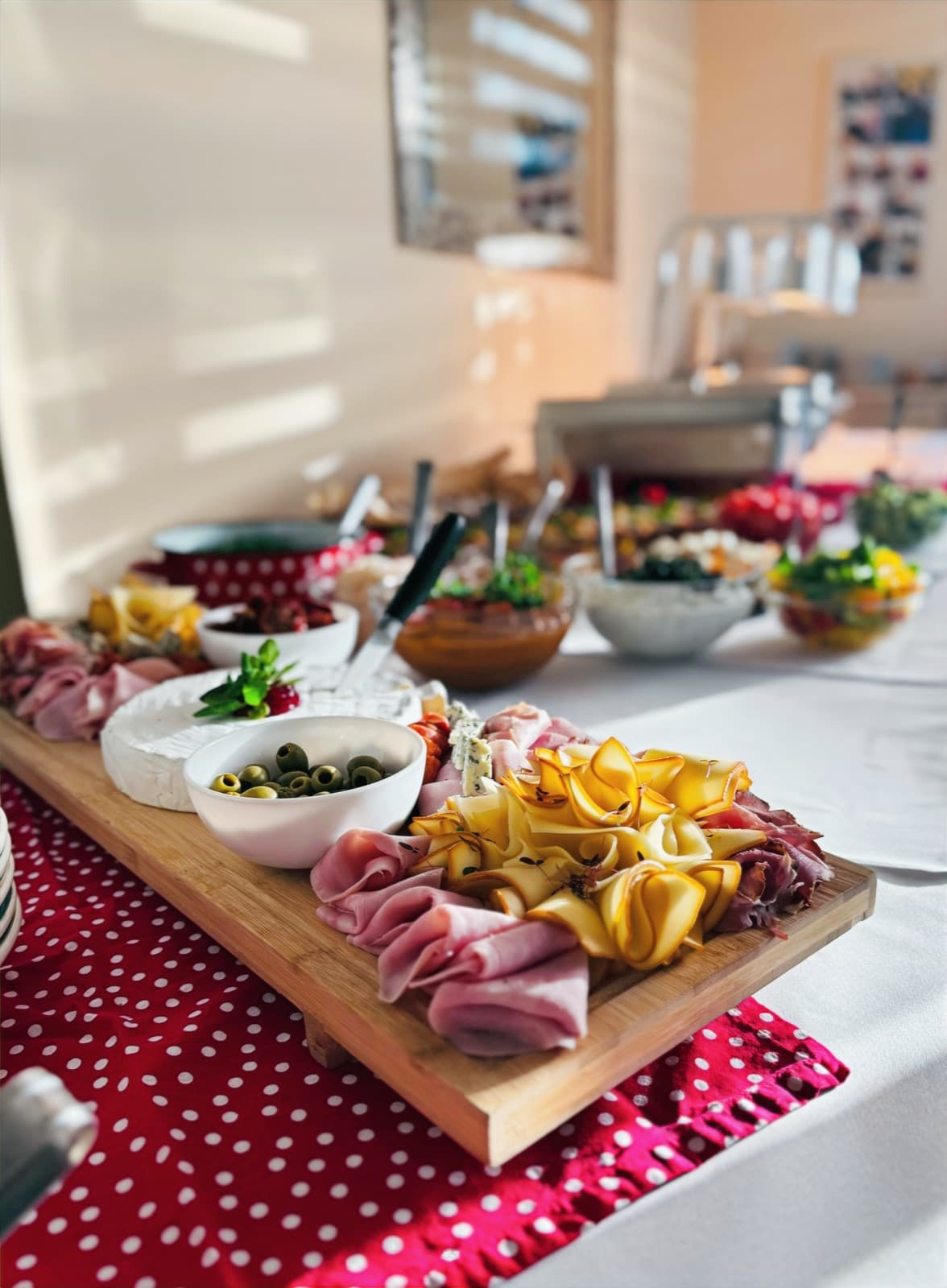 Wooden sharing platter loaded with cured meats, cheeses and sides