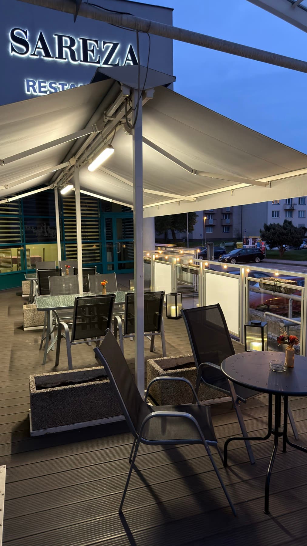 Krytá terasa restaurace Sareza s prostřenými stoly za soumraku