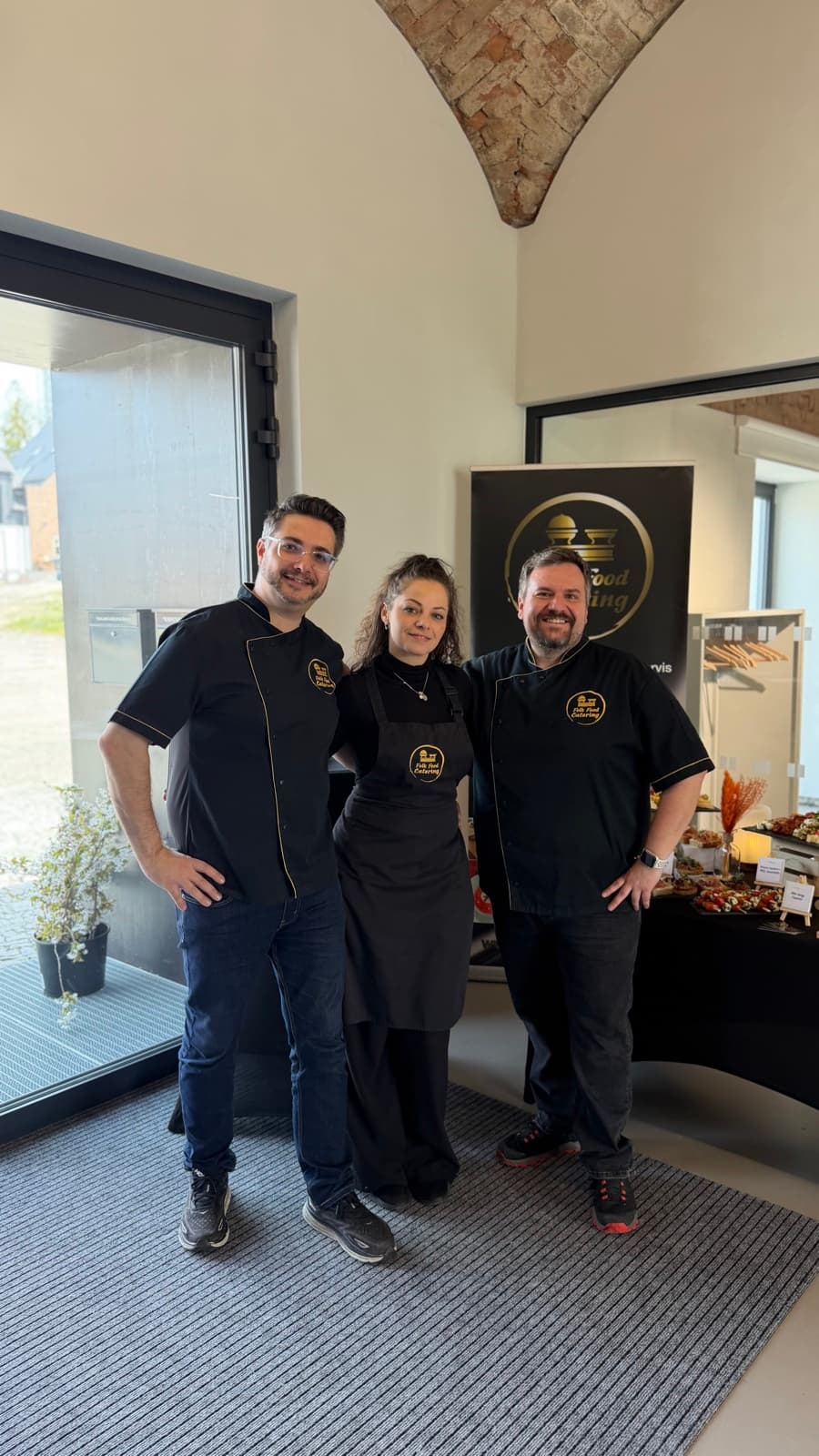 Tým Folk Food Catering v černo-zlatých rondonech před připraveným rautem